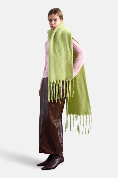Groene wintersjaal van TOPSHOP, met franjes, gecombineerd met een roze trui en bruine leren broek met laarzen.
