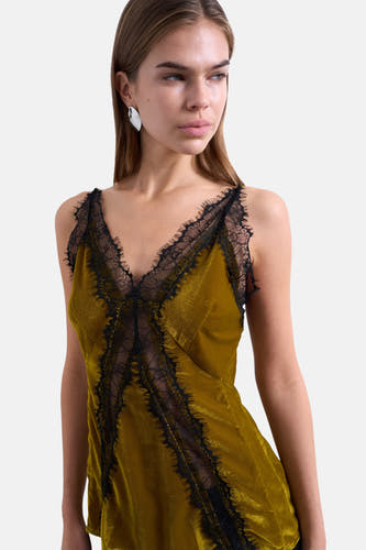 Blouse verte sans manches de TOPSHOP, terminée avec un bord noir le long des bords et du col en V.