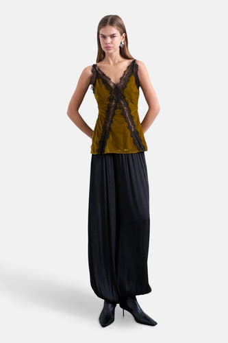 Blouse verte sans manches de TOPSHOP, avec des détails noirs sur les bords, associée à une jupe noire et des bottines.