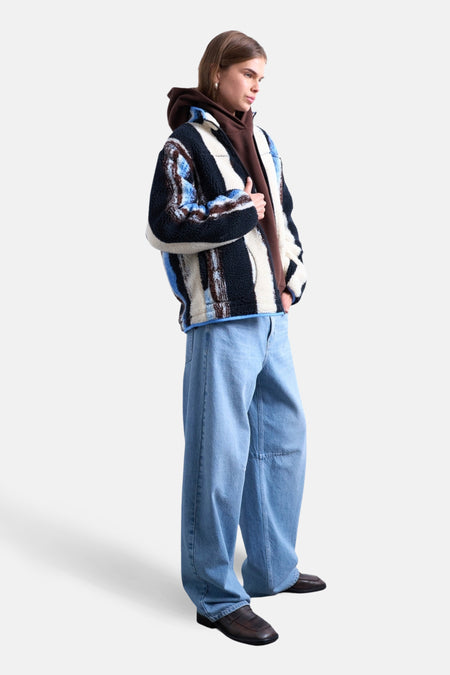 Model met hoodie, fleece jack, wijde jeans en loafers.