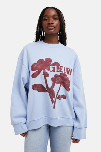 Gilet bleu avec col rond de TOPSHOP, imprimé de fleurs rouges et le texte 'FLEURI'.