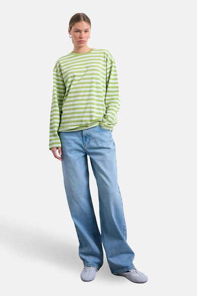 T-shirt à manches longues rayé vert de TOPSHOP, porté avec un jean ample et des baskets grises.