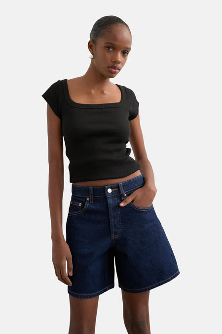 Short en jean bleu marine de TOPSHOP, avec coutures et un patch en cuir à l'arrière, porté avec un t-shirt noir.