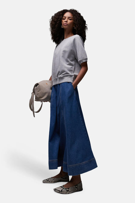 Lange mid-blauwe denim rok van TOPSHOP met wijde pasvorm en stiksels, gecombineerd met een grijs T-shirt en slangenprint schoenen.