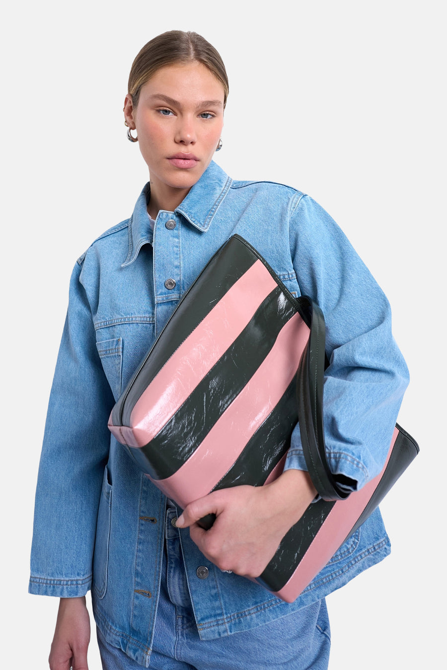 Sac à bandoulière rose de TOPSHOP, avec de larges rayures verticales noires, porté avec une veste en jean et un jean.