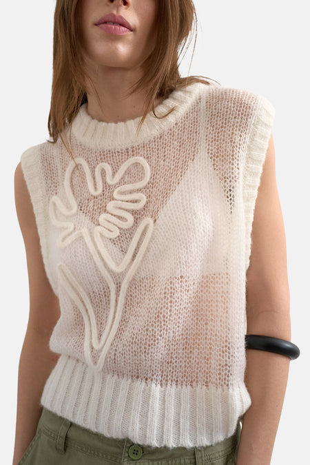 Gilet sans manches écru de TOPSHOP, avec un motif floral sur le devant, porté sur un haut blanc et un pantalon vert.