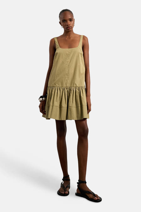 Robe verte sans manches de TOPSHOP, avec un décolleté droit et un ourlet de jupe plissé, combinée avec des bracelets argentés.
