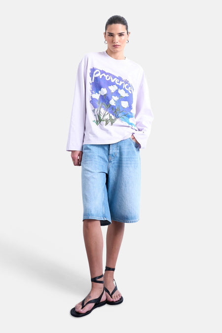 T-shirt à manches longues violet de TOPSHOP, avec un motif floral et porté avec un short en jean et des sandales noires.