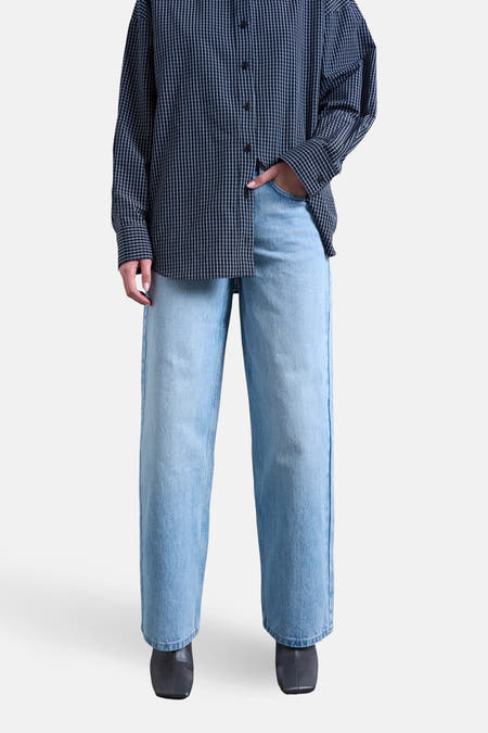 Jeans coupe ample en denim bleu clair de TOPSHOP, associés à une chemise à manches longues à carreaux et des bottes noires.