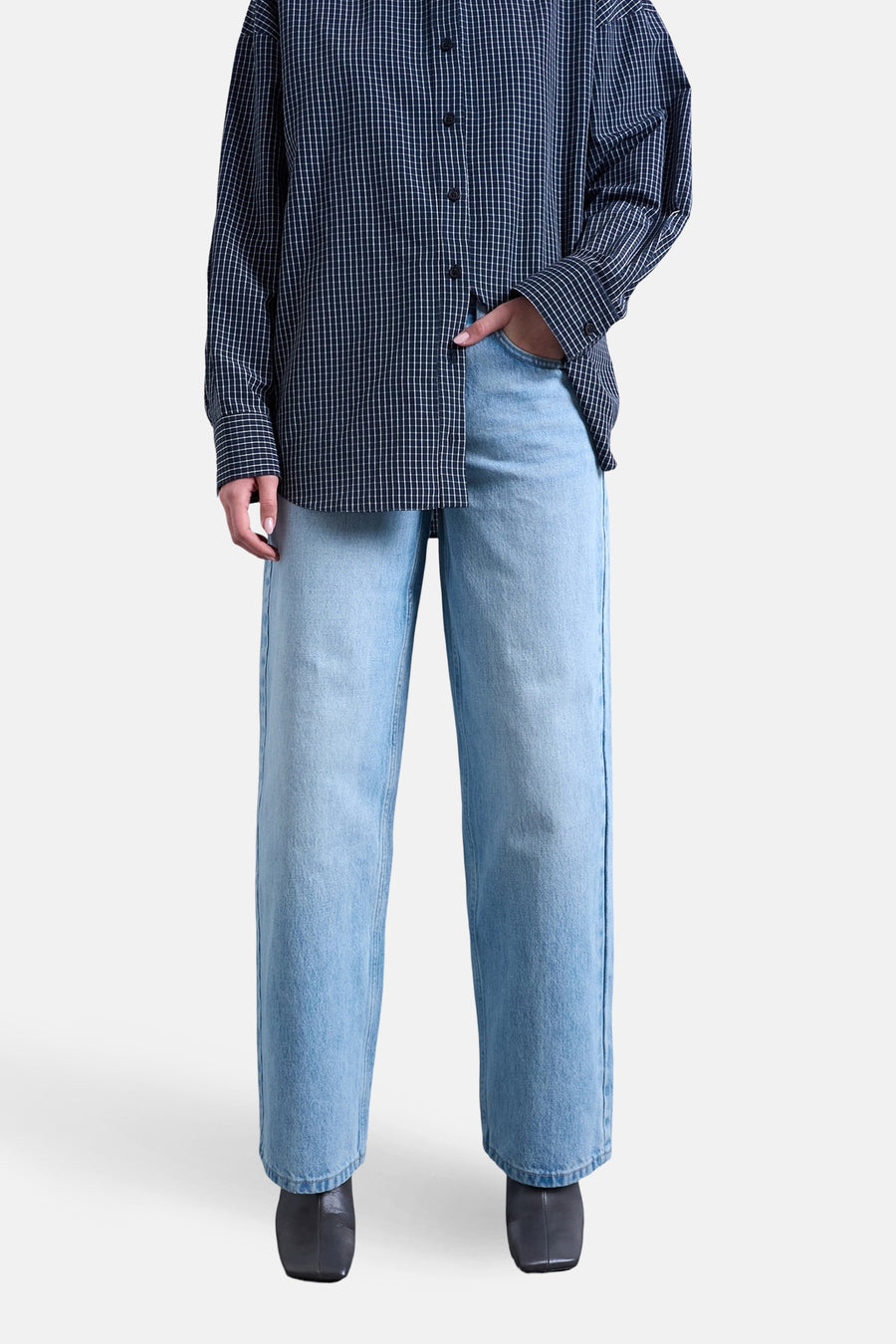 Jeans coupe ample en denim bleu clair de TOPSHOP, associés à une chemise à manches longues à carreaux et des bottes noires.