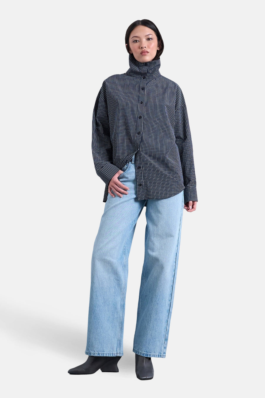 Jeans coupe ample en denim bleu clair de TOPSHOP, combinés avec une chemise à carreaux noir et blanc et des bottines noires.