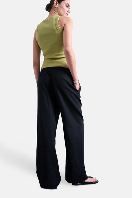 Pantalon noir TOPSHOP, avec une taille élastique et un cordon de serrage, porté avec un bracelet argenté.