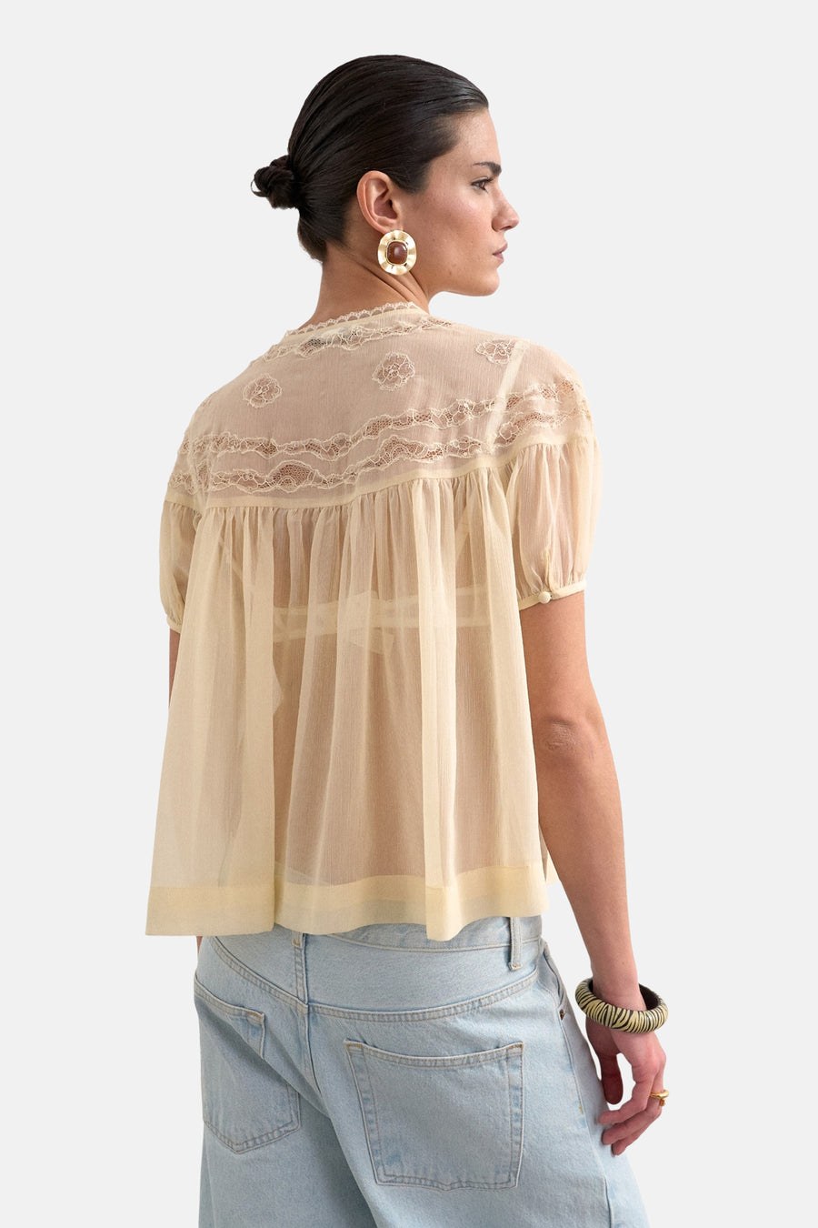 Ecru blouse met korte mouwen van TOPSHOP, met kanten details en gecombineerd met een jeans en een opvallende armband.
