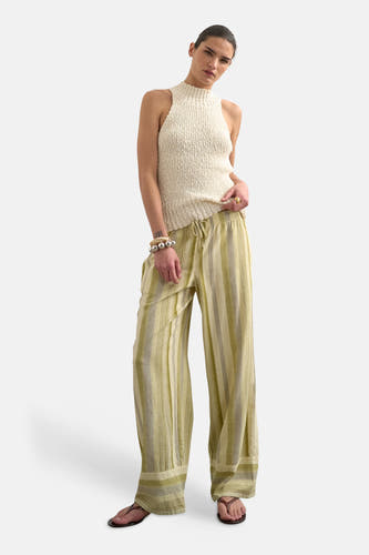 Groene broek met verticale strepen van TOPSHOP, gecombineerd met een mouwloze, gebreide top en sandalen.
