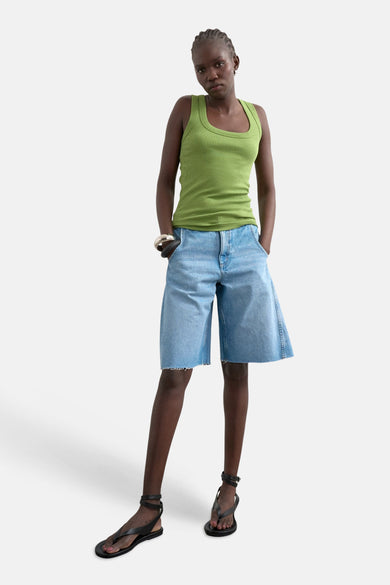 Débardeur vert TOPSHOP, avec une texture côtelée, associé à un short en jean ample et des sandales noires à lanières.