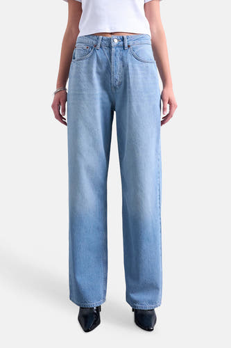 Jean droite bleu moyen de TOPSHOP, à jambes larges, porté par un mannequin avec un t-shirt blanc et des bottes noires.