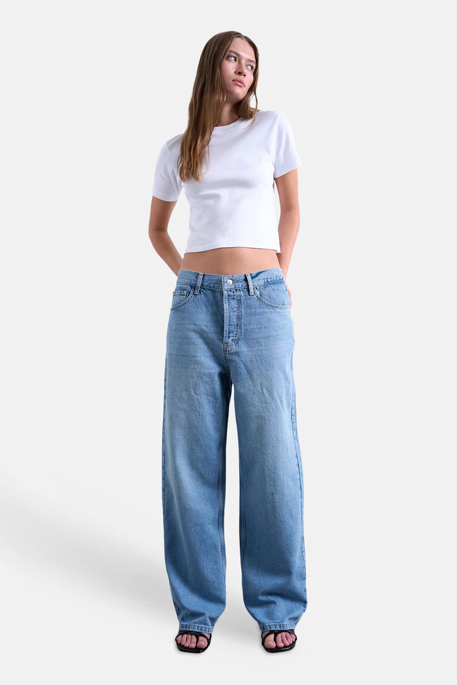 Jean droit bleu moyen TOPSHOP à jambes larges, porté par un mannequin dans un t-shirt blanc et des sandales noires.