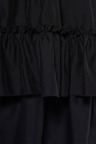 Robe noire TOPSHOP avec volants superposés et un tissu doux et fluide, gros plan.