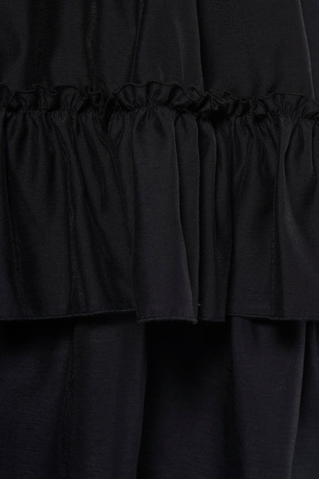 Robe noire TOPSHOP avec volants superposés et un tissu doux et fluide, gros plan.