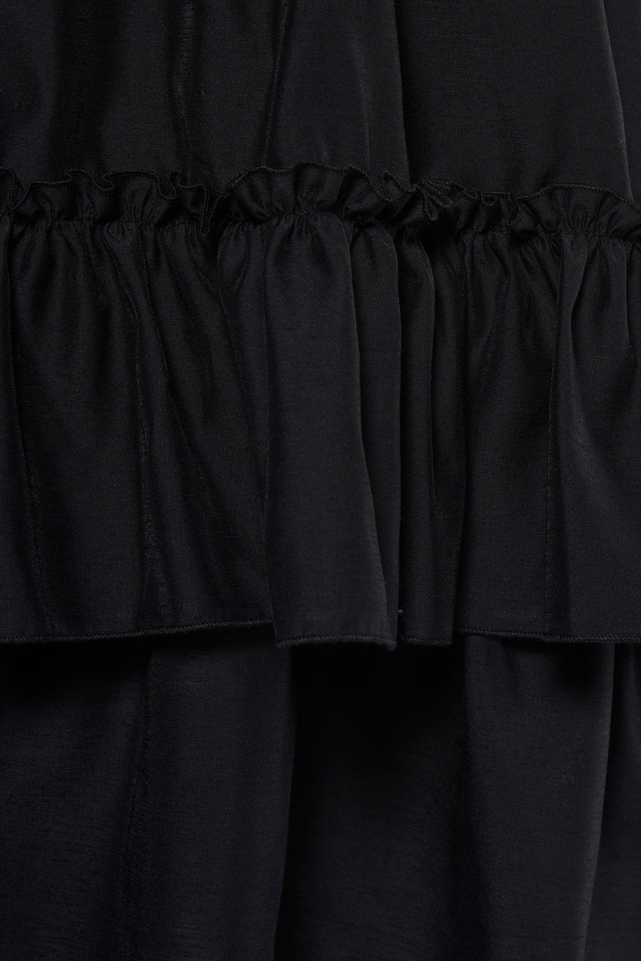 Robe noire TOPSHOP avec volants superposés et un tissu doux et fluide, gros plan.
