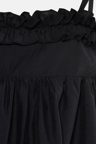 Détail d'une robe noire TOPSHOP avec volants sur le dessus et tissu plissé.
