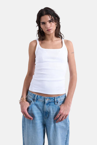 Débardeur blanc de TOPSHOP, porté avec un jean bleu ample et des bracelets dorés.