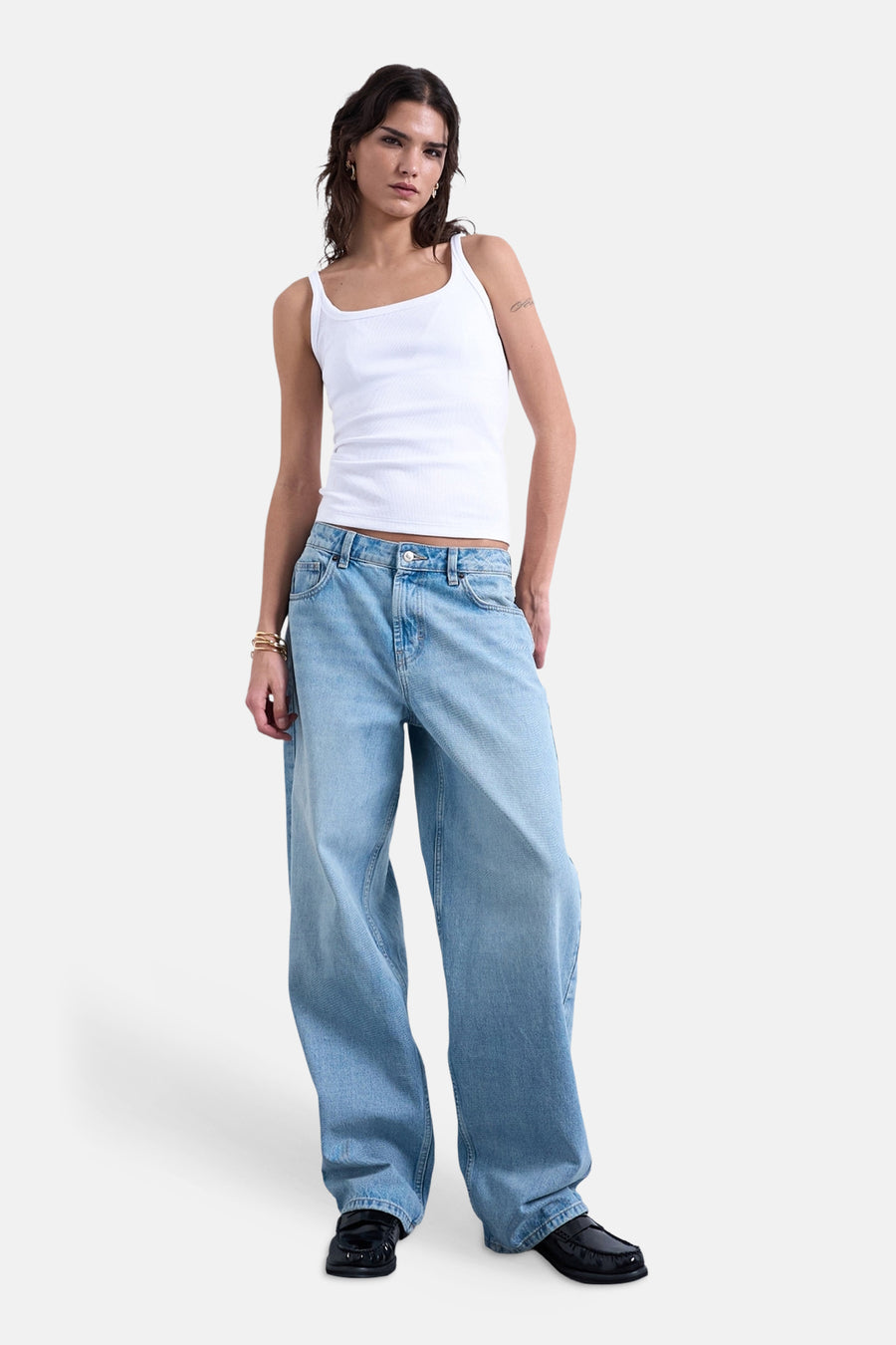 Débardeur blanc de TOPSHOP, porté avec un jean ample et des mocassins noirs.
