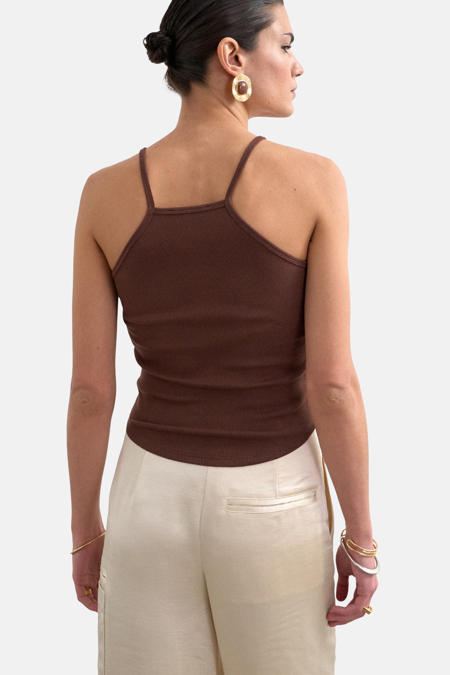 Bruine geribbelde top met spaghettibandjes van TOPSHOP, van achteren gezien op een model met lichte broek en sieraden.