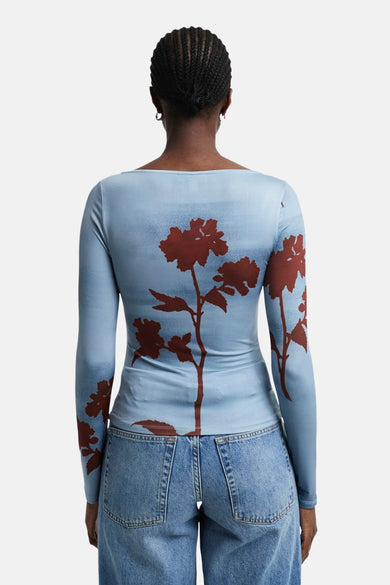 T-shirt bleu à manches longues de TOPSHOP, avec une impression de fleurs brunes sur le dos, associé à un short en denim.