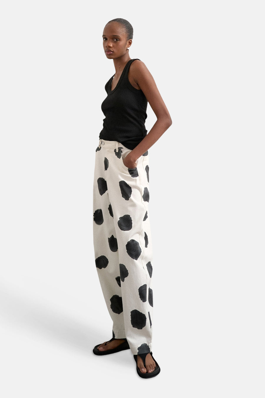 Pantalon écru de TOPSHOP à grands pois noirs, porté avec un débardeur noir et des sandales noires.