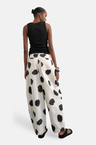 Pantalon écru de TOPSHOP, à motif à pois noirs, combiné avec un top noir sans manches et des sandales.