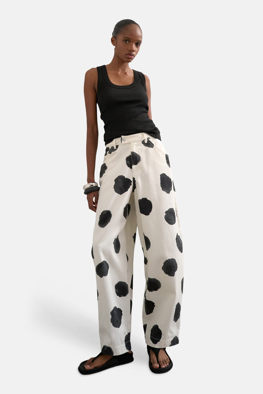 Ecru broek van TOPSHOP met grote zwarte stippen, gedragen met een zwarte tanktop en zwarte sandalen.
