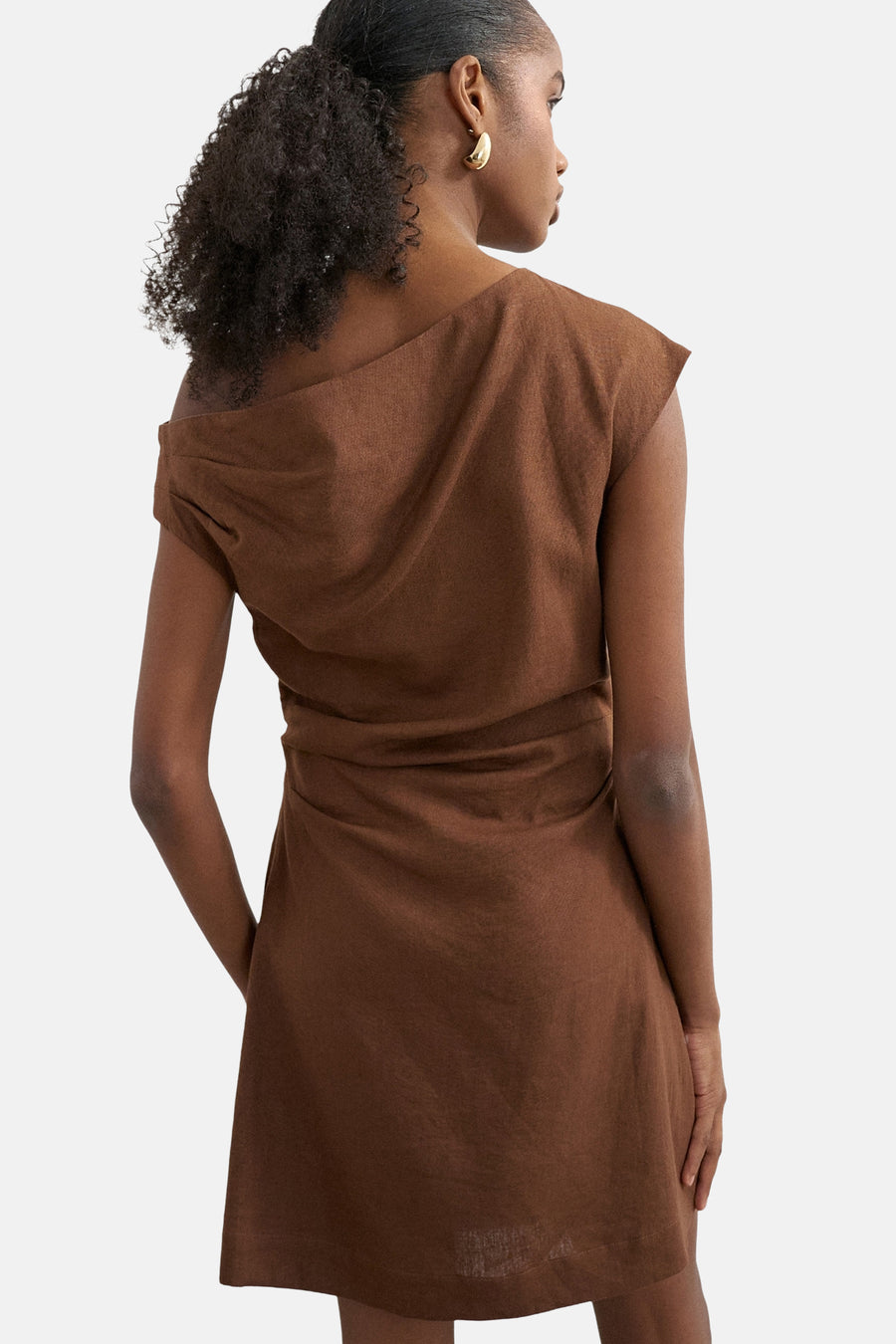 Bruin kleedje met korte mouwen van TOPSHOP, achterkant gezien, met gedrapeerde rug en gouden oorbel.