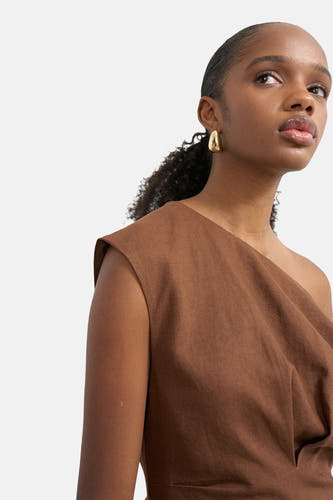 Robe asymétrique marron de TOPSHOP, en tissu texturé, portée par une femme avec des boucles d'oreilles dorées.