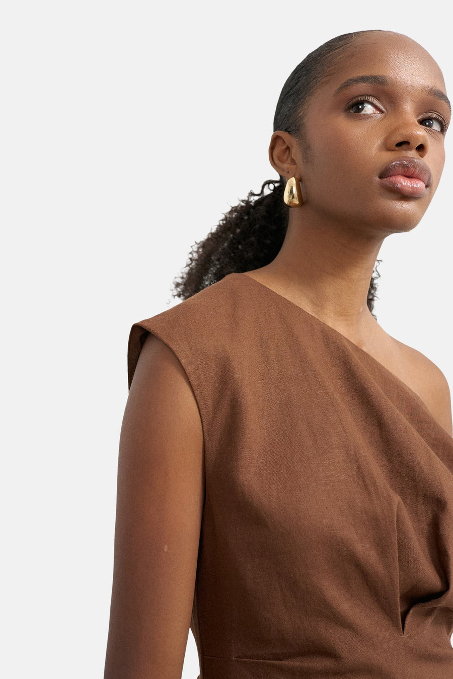 Robe asymétrique marron de TOPSHOP, en tissu texturé, portée par une femme avec des boucles d'oreilles dorées.