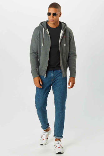 Pull-over gris avec fermeture à glissière de Levi's, porté avec un T-shirt noir, des jeans bleus et des baskets blanches.