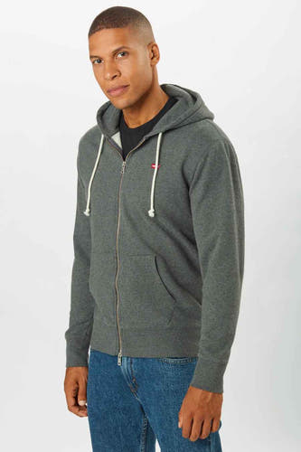 Veste grise de Levi's, avec fermeture éclair et capuche, portée sur un t-shirt noir et des jeans bleus.