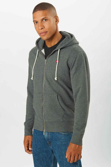 Veste grise de Levi's, avec fermeture éclair et capuche, portée sur un t-shirt noir et des jeans bleus.
