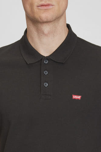 Polo noir à manches courtes de Levi's, avec une étiquette rouge sur la poitrine.