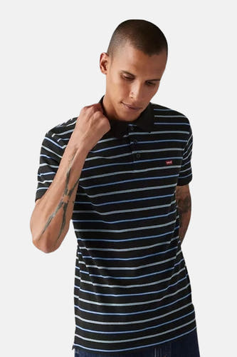 Polo rayé bleu de Levi's à manches courtes, dos, associé à des jeans foncés et des tatouages sur les bras.