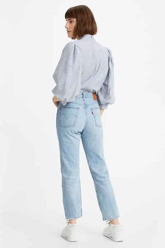 Femme, chemise rayée, jeans légers, baskets blanches.