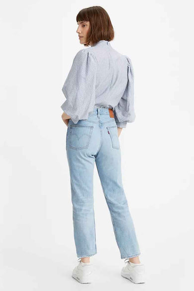 Femme, chemise rayée, jeans légers, baskets blanches.