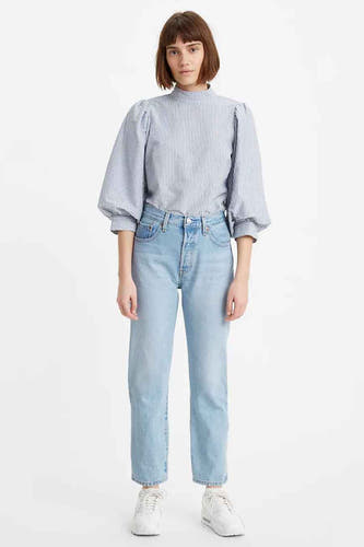 Femme en chemise rayée bleu et blanc et jeans bleu clair.