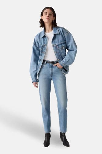 Jean droit en denim bleu clair de Levi's, associé à un t-shirt blanc, une veste en denim et des bottes noires.