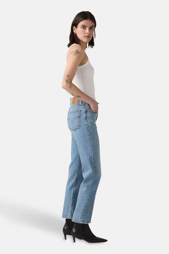 Rechte jeans van lichtblauw denim van Levi's®, gedragen met een witte tanktop en zwarte laarsjes, in zijaanzicht.
