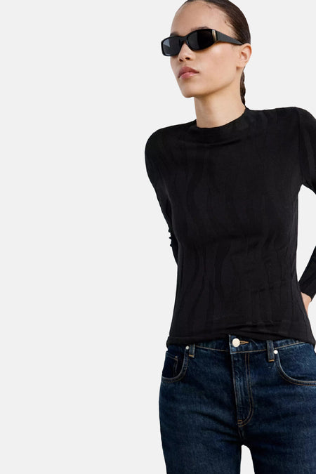 Zwarte ronde hals trui van MANGO, met textuurpatroon, gedragen met donkerblauwe jeans en zonnebril, zijprofiel.