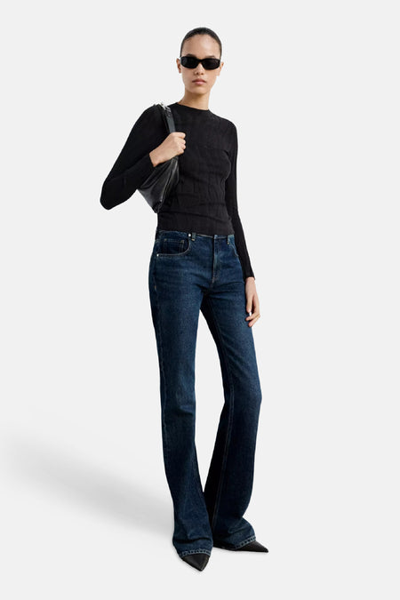 Zwarte ronde hals trui van MANGO, met ribstructuur, gedragen met donkerblauwe flared jeans en zwarte zonnebril, lifestyle shot.