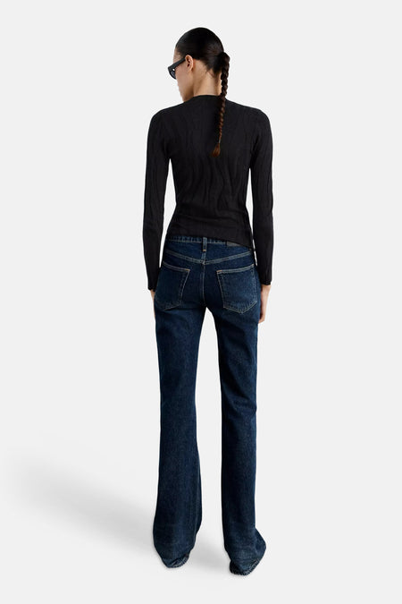 Zwart gebreid trui met ronde hals van MANGO, achterzijde weergegeven, met fijn kabelpatroon en strakke pasvorm, gedragen met donkerblauwe flared jeans.