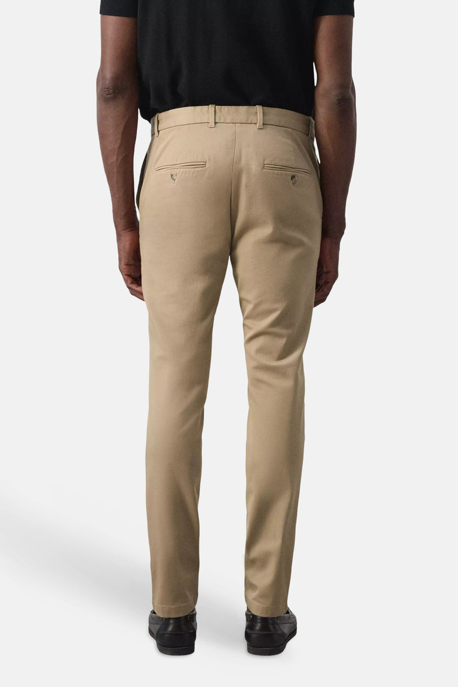 Beige chino broek van MANGO, achterkant weergegeven met twee zakken en strakke pasvorm, gedragen met zwart shirt en zwarte schoenen.