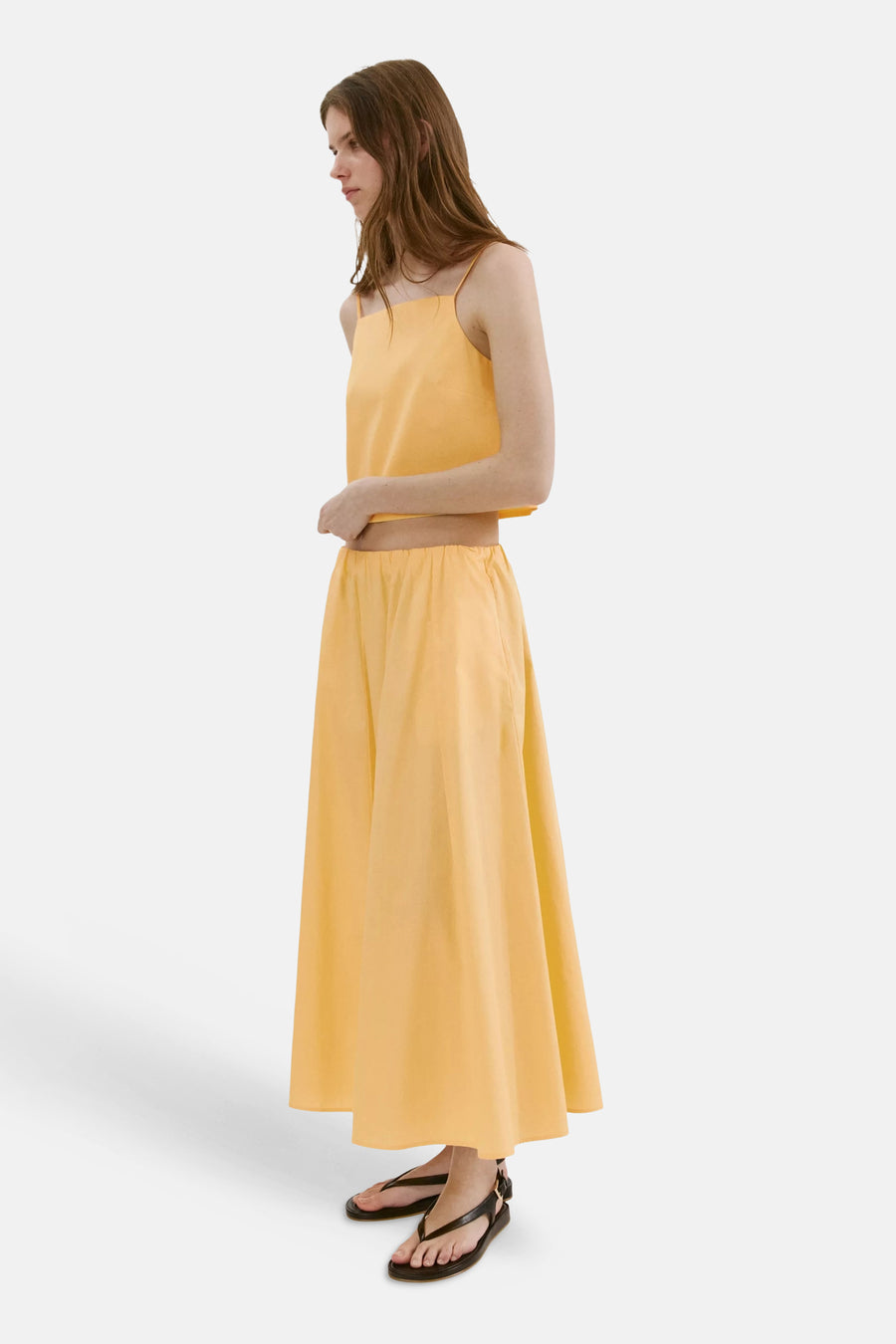 Gele casual rok van MANGO, zijprofiel, met elastische taille en vloerlange A-lijn, gedragen met bijpassend topje en zwarte sandalen.